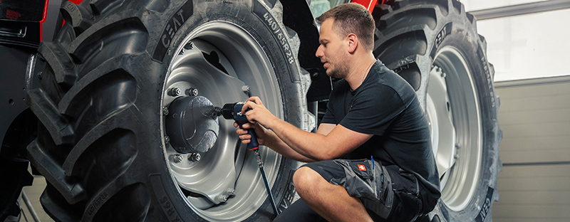 Person, die ein Rad an einem Traktor montiert.