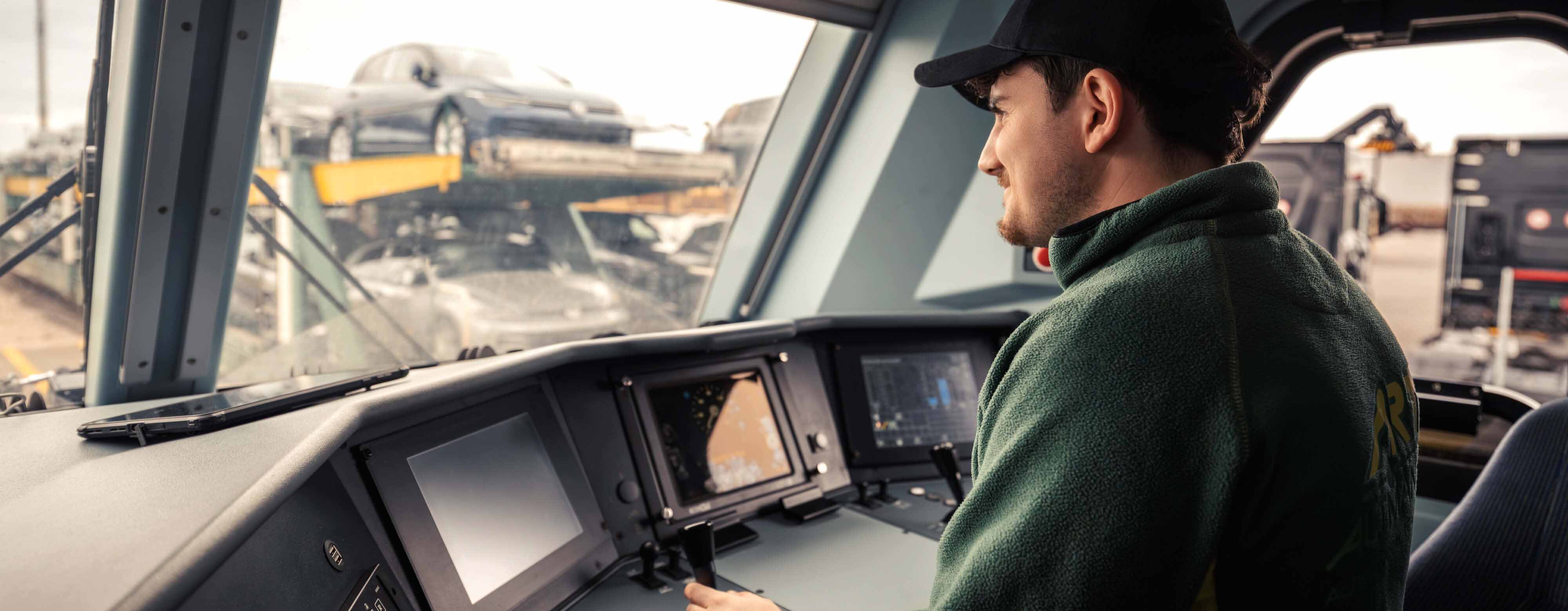 Person im Cockpit einer Lok mit Blick aus dem Fenster.