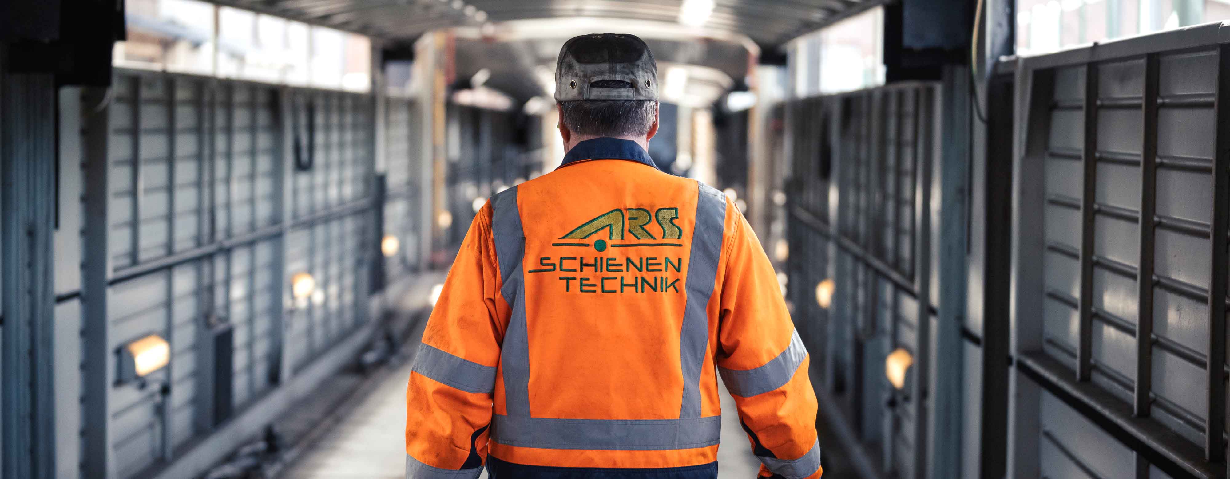 Person von hinten mit dem Aufdruck "ARS Schienentechnik" auf der Jacke.